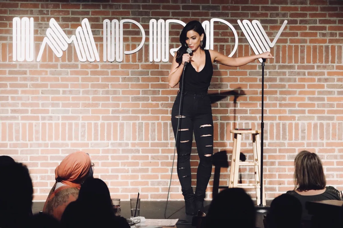 Performing to a seated crowd against the brick wall of an Improv club